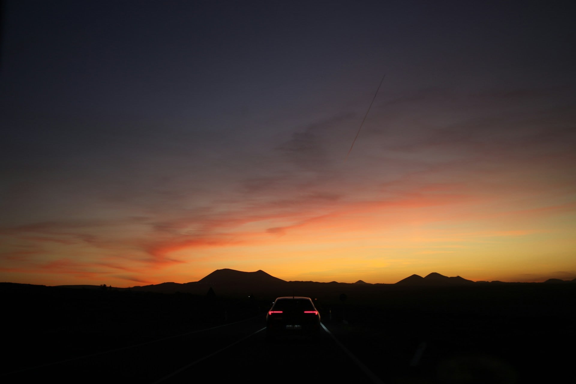 Car silhouette against a dramatic sunset sky